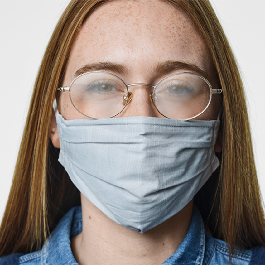 Person wearing a light blue fabric mask and glasses, with lenses fogged up.