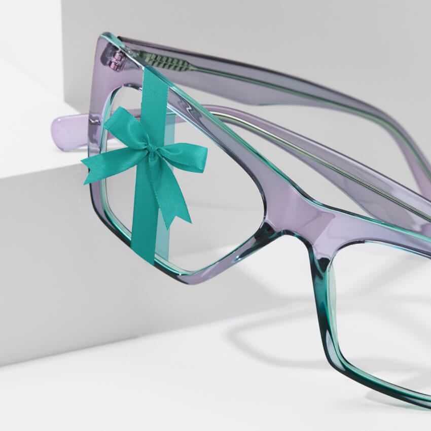 Purple and teal eyeglasses with a teal ribbon bow on the left lens.
