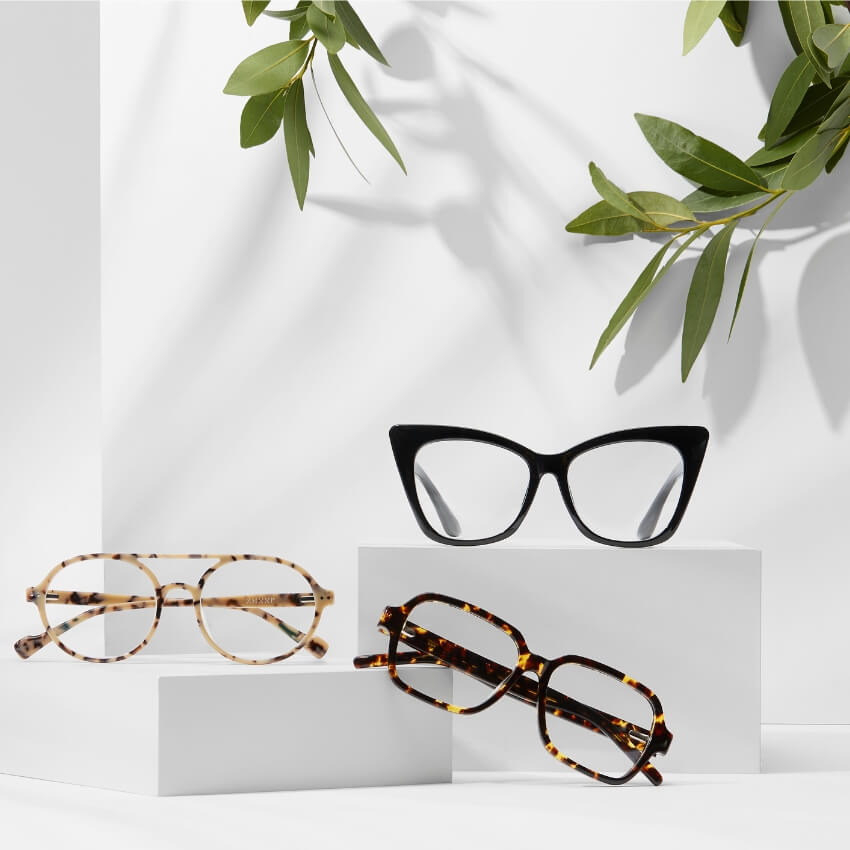 Three pairs of eyeglasses: black cat-eye, tortoiseshell oval, and tortoiseshell square frames.