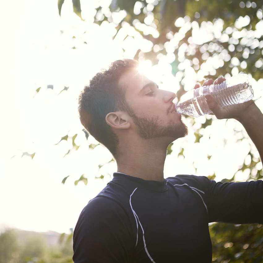 Man drinking water from a plastic bottle.