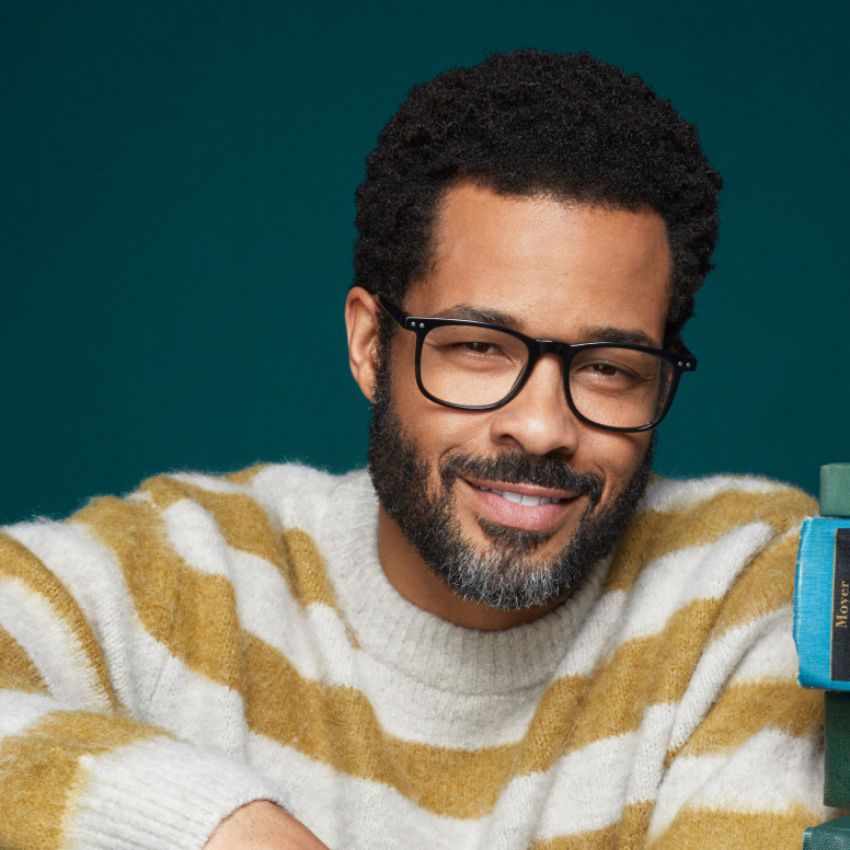 Man wearing striped sweater and black glasses, smiling.